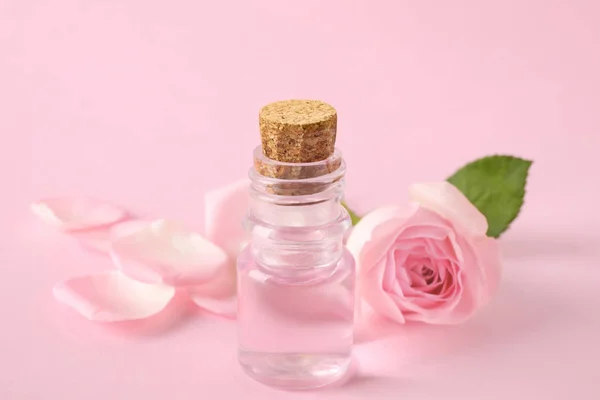 Fles etherische olie en Rose op roze achtergrond — Stockfoto