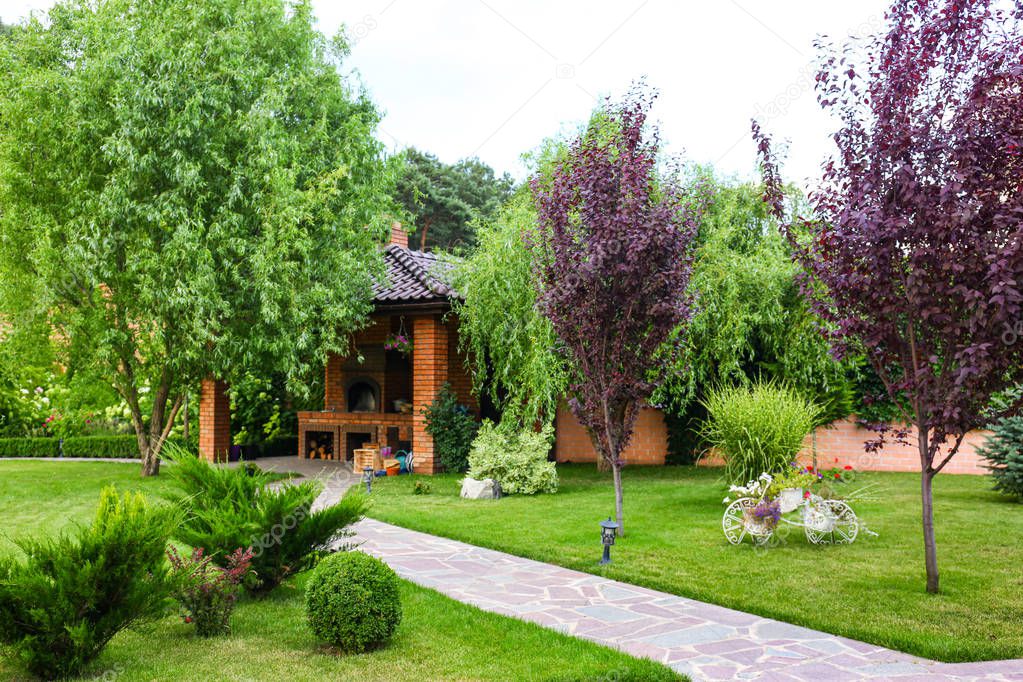 Landscape with beautiful green garden and gazebo on summer day