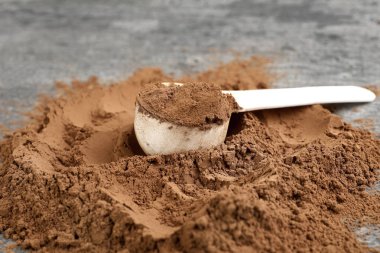 Çikolata protein tozu yığını ve gri masaya kepçe, closeup