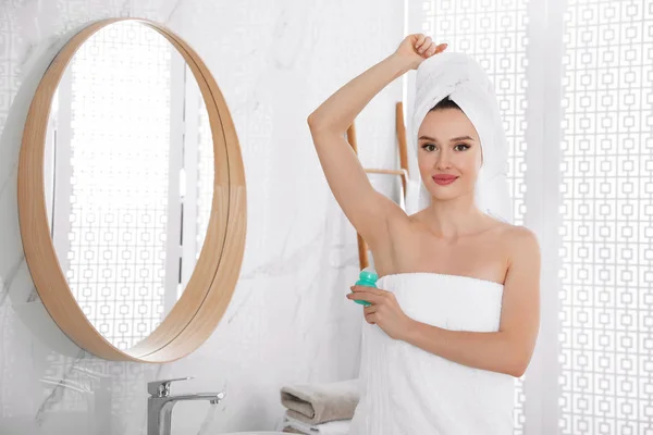 Hermosa mujer joven aplicando desodorante después de la ducha en el baño — Foto de Stock