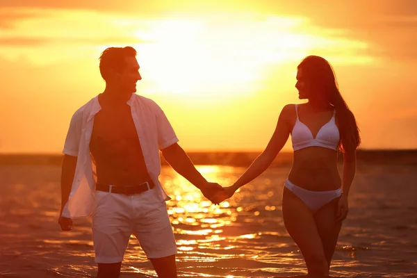 Feliz jovem casal passar tempo juntos na praia do mar ao pôr do sol — Fotografia de Stock