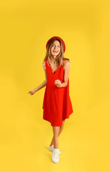 Mooie jonge vrouw in rode jurk dansen op gele achtergrond — Stockfoto