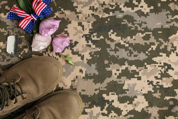 Composición plana con botas militares y flores sobre fondo de camuflaje, espacio para texto. Día de las Fuerzas Armadas — Foto de Stock