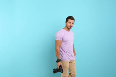 Açık mavi arka plan profesyonel kamera ile genç fotoğrafçı. Metin için alan