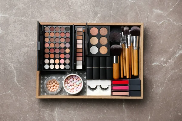 Set of different professional makeup products in box on table, top view