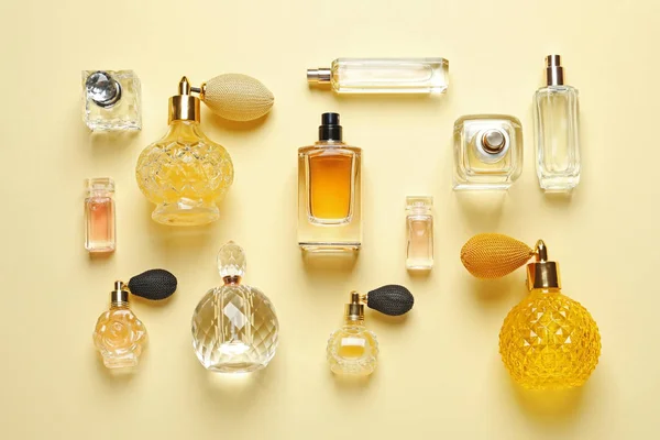 Плоская композиция с различными парфюмерными бутылками на светло-желтом фоне — стоковое фото