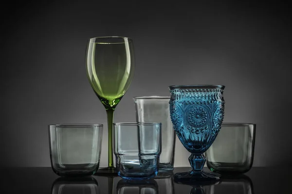 Ensemble de différents verres vides colorés sur la table sur fond gris — Photo