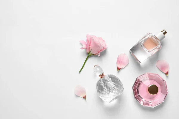 Diferentes botellas de perfume y flores sobre fondo blanco, vista superior — Foto de Stock