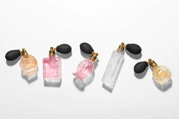 Différentes bouteilles de parfum élégantes sur fond blanc, vue de dessus — Photo