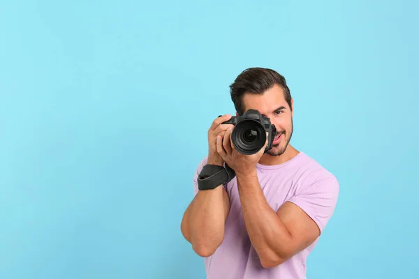 年轻的专业摄影师在浅蓝色背景上拍照。文本空间 — 图库照片