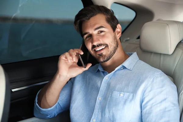 Atrakcyjny młody człowiek rozmawia na telefon w luksusowym samochodzie — Zdjęcie stockowe
