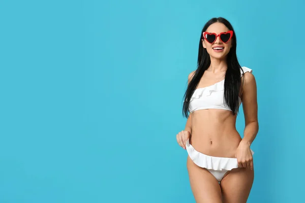 Hermosa joven en bikini blanco con gafas de sol sobre fondo azul claro. Espacio para texto —  Fotos de Stock