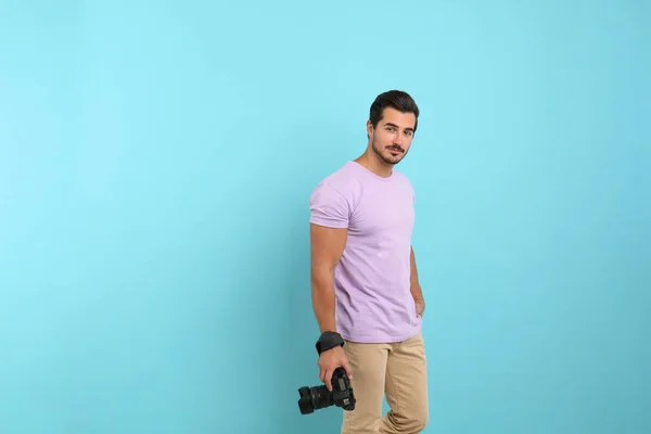 Молодой фотограф с профессиональной камерой на светло-голубом фоне. Пространство для текста — стоковое фото