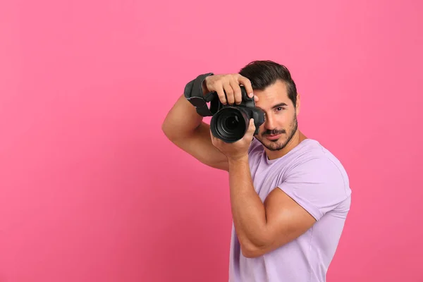 Mladý profesionální fotograf fotografi na růžovém pozadí. Místo pro text — Stock fotografie