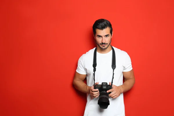 Jovem fotógrafo com câmera profissional em fundo vermelho. Espaço para texto — Fotografia de Stock