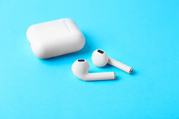 Earphone nirkabel modern dan pengisian kasus pada latar belakang biru muda — Stok Foto