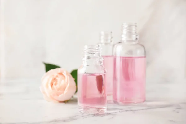 Láhve základního oleje a růžové na mramorovém stole — Stock fotografie