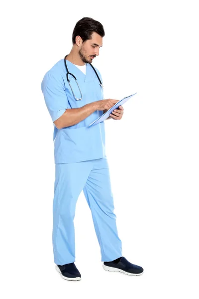 Joven doctor en uniforme con estetoscopio y portapapeles sobre fondo blanco. Servicio médico — Foto de Stock