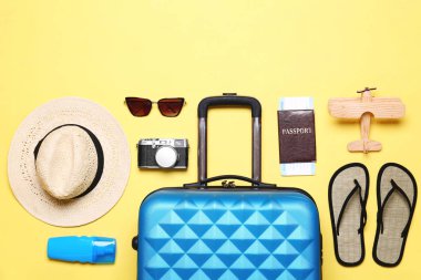 Sarı arka plan üzerinde bavul ve plaj nesneleri ile düz yatıyordu kompozisyon