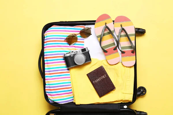 Offener Koffer mit Strandobjekten auf gelbem Hintergrund, Draufsicht — Stockfoto