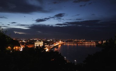 Kiev, Ukrayna - 21 Mayıs 2019: Nehir ve köprüye yakın ışıklı binalarla gece şehir manzarasının güzel manzarası