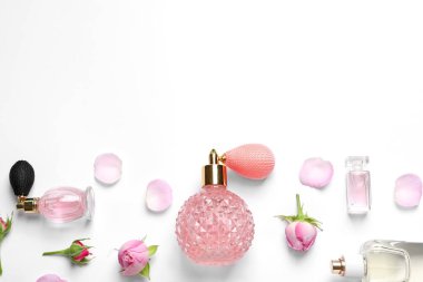 Beyaz arka planda farklı parfüm şişeleri ve çiçekler, üst görünüm