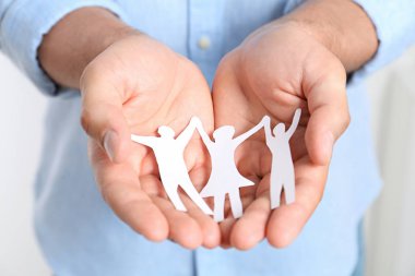 Kağıt aile figürü tutan genç adam, elleri yakın çekim