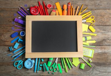 Ahşap arka plan üzerinde farklı okul kırtasiye ve boş küçük tebeşir tahtası, düz yatıyordu. Metin için alan