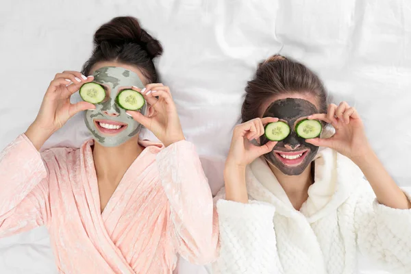 Fiatal barátok arc maszkok szórakozik az ágyban kényeztesse party, felülnézet — Stock Fotó