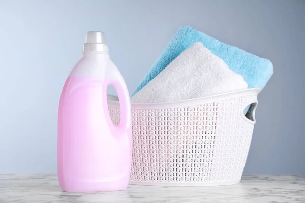 Bottle of laundry detergent and basket with towels on table