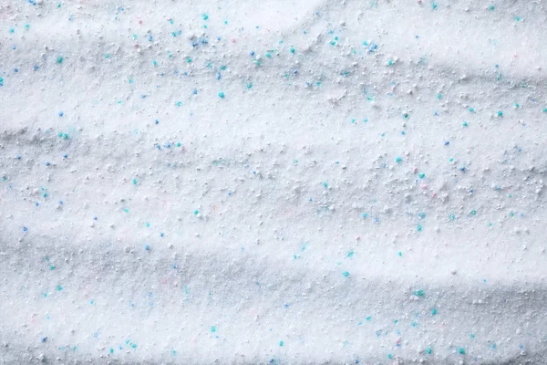 Detergente em pó de lavandaria com grânulos de cor como fundo, vista superior — Fotografia de Stock