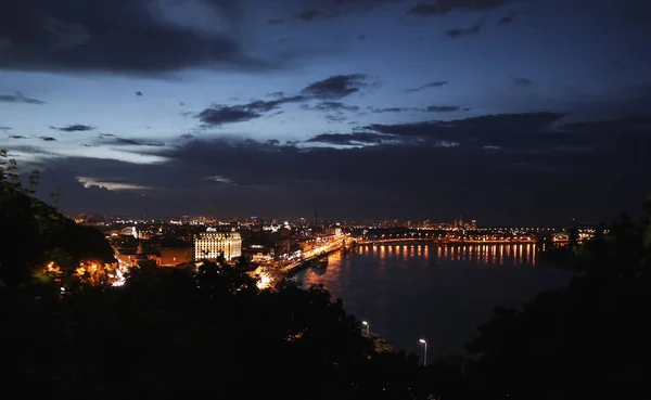 Kijów, Ukraina-21 maja 2019: piękny widok na nocny pejzaż z podświetlanymi budynkami w pobliżu rzeki i mostu — Zdjęcie stockowe