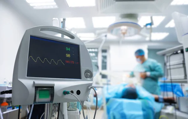 Zamazany widok lekarza przygotowujący się do zabiegu chirurgicznego w sali operacyjnej, skupić się na monitorze pacjenta — Zdjęcie stockowe