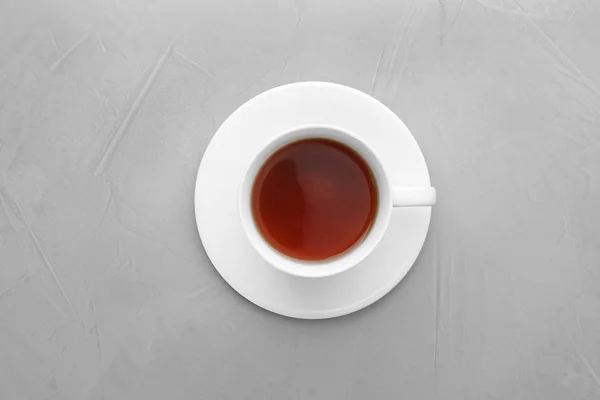 Šálek čaje a talíře na šedém pozadí, pohled shora — Stock fotografie