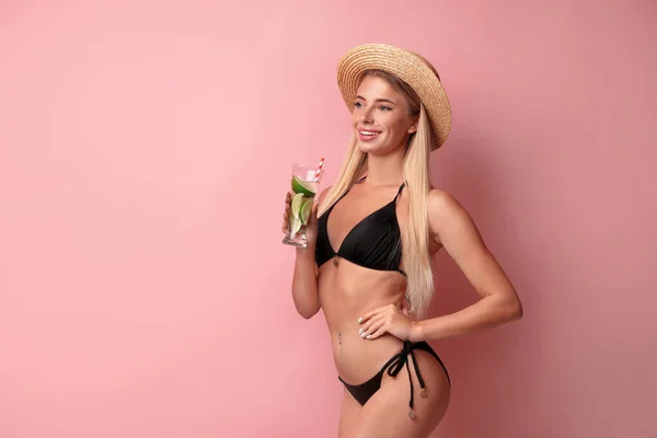 Mooie jonge vrouw draagt stijlvolle bikini met cocktail op roze achtergrond — Stockfoto