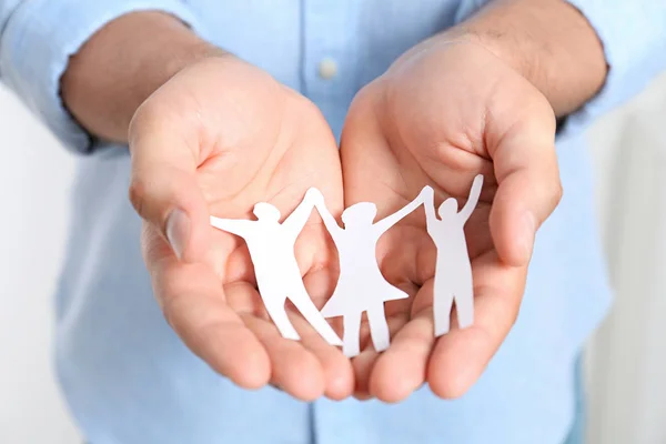 Young man holding paper family figure, closeup of hands — Stock Photo, Image