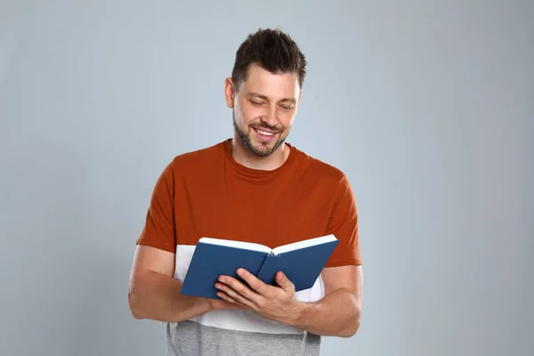 Schöner Mann liest Buch auf hellem Hintergrund — Stockfoto
