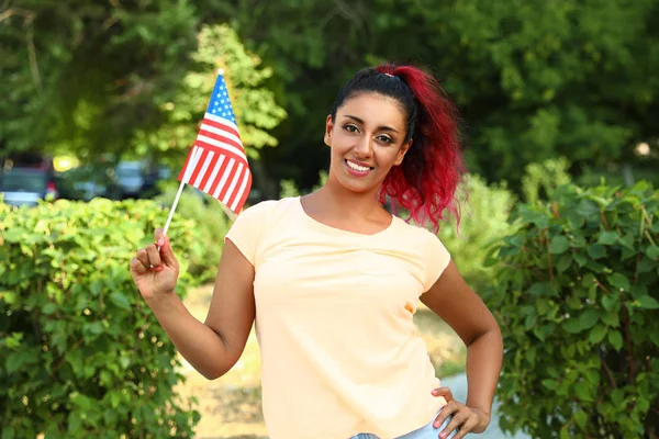 Beautiful Hispanic woman with US flag in park