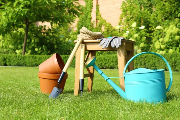 Set of gardening tools and stool on green grass — Stock Photo, Image