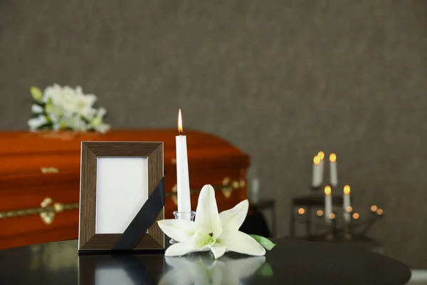Černý fotografický rám s hořící svíčkou a bílou lilií na stole v pohřebním ústavu — Stock fotografie