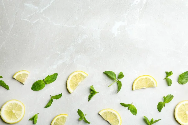 Fresh mint with sliced lemon on grey marble background, flat lay. Space for text — Stock Photo, Image