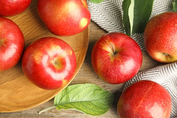 Pommes rouges juteuses mûres sur fond bois, plat — Photo