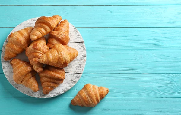 Board ízletes croissant és hely a szöveg világos kék háttér, lapos feküdt. Francia cukrászsütemény — Stock Fotó