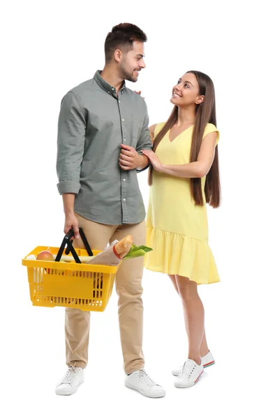 Νεαρό ζευγάρι με καλάθι αγορών γεμάτο προϊόντα απομονωμένα σε λευκό — Φωτογραφία Αρχείου