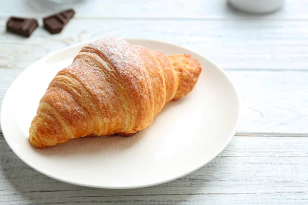 Placa con sabroso croissant sobre mesa de madera blanca, primer plano. Pastelería francesa — Foto de Stock