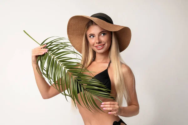 Mulher bonita vestindo biquíni elegante com folha de palma no fundo claro — Fotografia de Stock