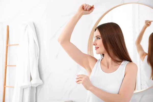 Vacker ung kvinna som ansöker deodorant i Bad rums. Utrymme för text — Stockfoto