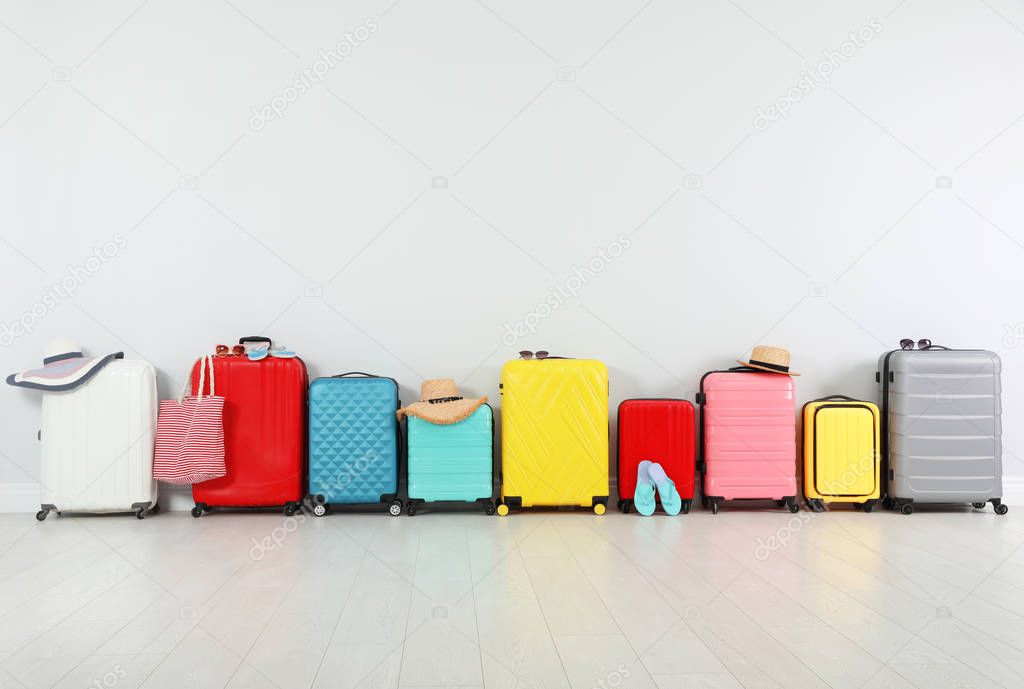 Trendy composition with colorful suitcases near light wall. Space for text