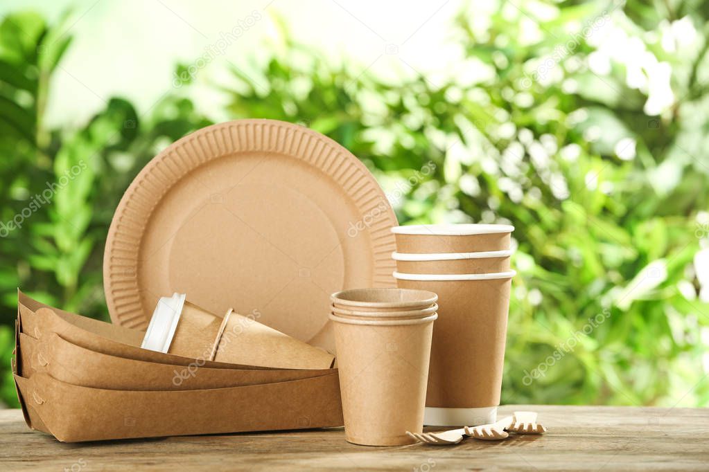 Paper dishware on wooden table against blurred background, space for text