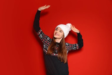 Kırmızı arka planda Noel süveteri giyen genç kadın